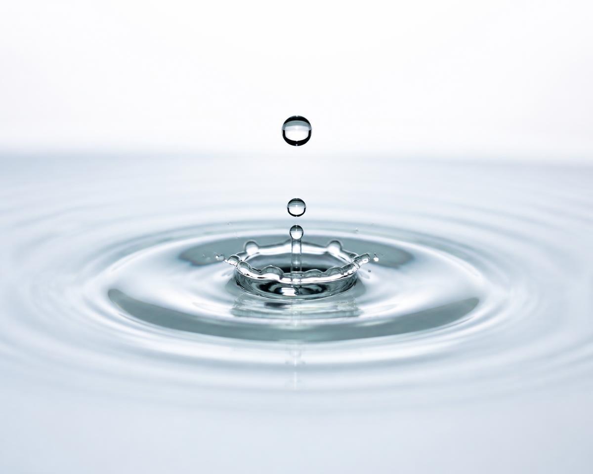 A water droplet splash seen from the side, sending ripples outward